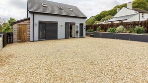 A modern building with a gravel driveway, a wooden fence, and a garden area.