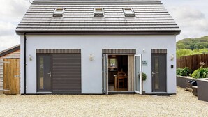 A modern building with two garage doors, a small window, and a door leading to an interior space.
