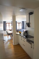 Una cocina compacta con armarios blancos, una encimera negra y un área de comedor con una mesa y sillas.