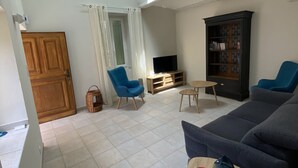 Un salon spacieux avec un plafond haut, un téléviseur, une bibliothèque et une grande fenêtre.