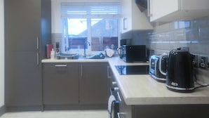 A compact kitchen with modern appliances, including a coffee maker and a microwave. - 2 bedroom accommodation in Whitstable (Whitstable)