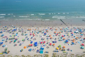 A beach with numerous colorful umbrellas and beach chairs, indicating a popular tourist spot.