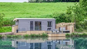 Une maison moderne dotée d’une terrasse donnant sur une piscine aux eaux cristallines, le tout entouré de verdure.