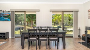 Un comedor con una mesa y sillas de madera oscura, ventanas grandes con cortinas y una chimenea.
