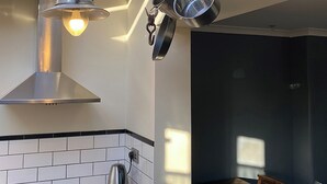 A kitchen with a stainless steel range hood, a kettle, and hanging pots. - Southfield Art Studio (Braunston, near Daventry)