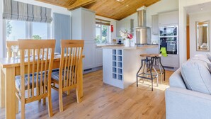 Una cocina moderna con vigas de madera en el techo, un comedor con sillas de madera y un taburete de bar.