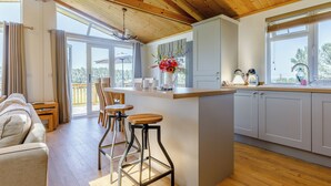 Una cocina moderna con vigas de madera, una barra y un espacio comedor con sofá y sillas.