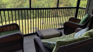 Een balkon met rieten meubilair en uitzicht op een groen landschap.