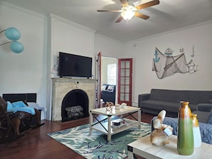 Una sala de estar con chimenea, televisor, sofá, mesa de centro y objetos decorativos.