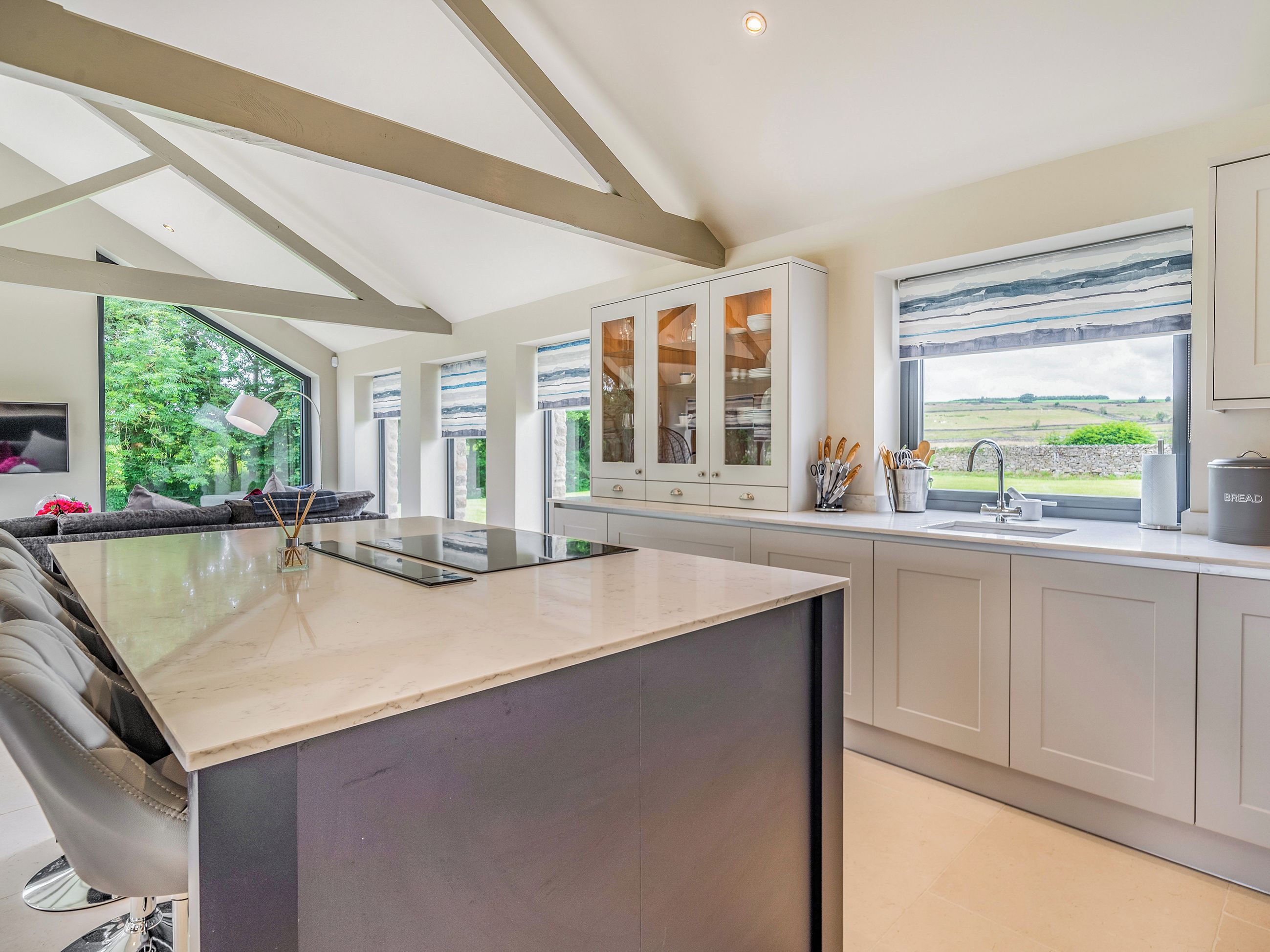 A modern kitchen with a large island, white cabinetry, and a view of the countryside.