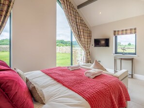 A bedroom with a large bed, a TV, and a view of the outdoors.