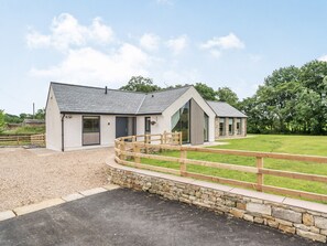 A modern building with a stone wall, a wooden fence, and a grassy area.