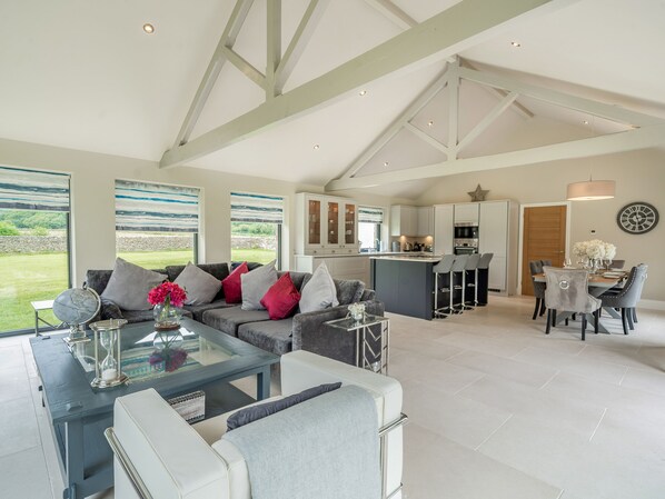 A spacious living area with a sofa, coffee table, and a dining table with chairs.
