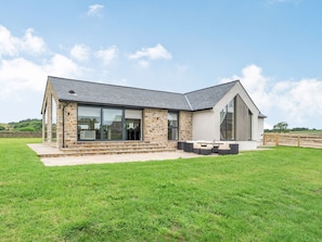 A modern house with a stone exterior, large windows, and a patio area.
