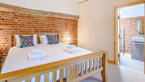 A bedroom with a brick wall, wooden bed frame, and a view to a bathroom.