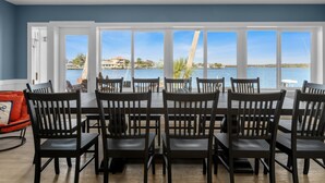 Un espace repas avec vue sur un lac, comprenant une grande table et des chaises, ainsi qu’un ventilateur de plafond.