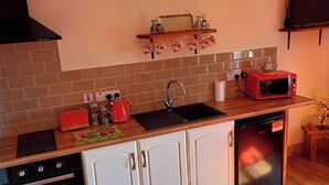 Kompakti keittiö, jossa on sisäänrakennettu uuni, astianpesukone, mikroaaltouuni ja pesuallas.