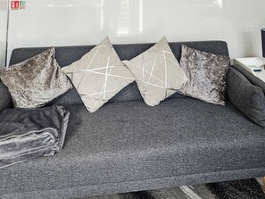 A grey sofa with three decorative pillows, one of which has a geometric pattern.