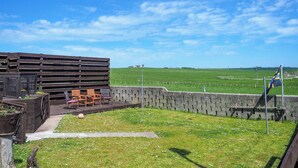 Een moderne buitenzitplaats met uitzicht op een groen veld en heldere lucht.