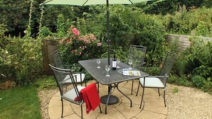 An outdoor patio with a table and chairs, a green umbrella, and a bottle of wine. - 2 bedroom accommodation in Snodland (Snodland)