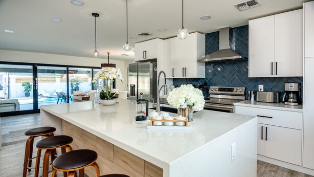 A modern kitchen with a large island, bar stools, stainless steel appliances, and a view to the outside. - Scottsdale Luxury Escape (Scottsdale)