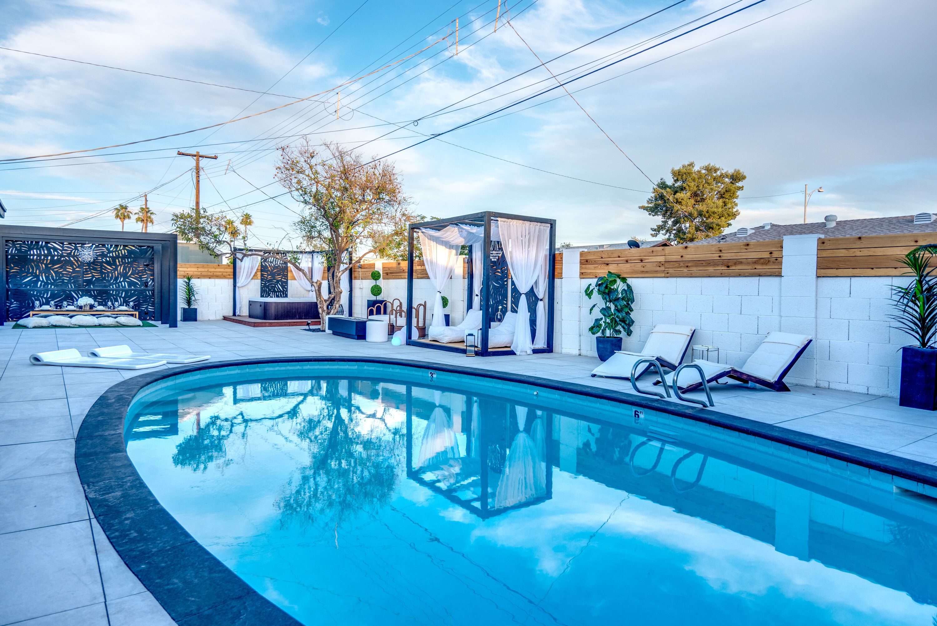 A swimming pool with lounge chairs and a covered seating area.