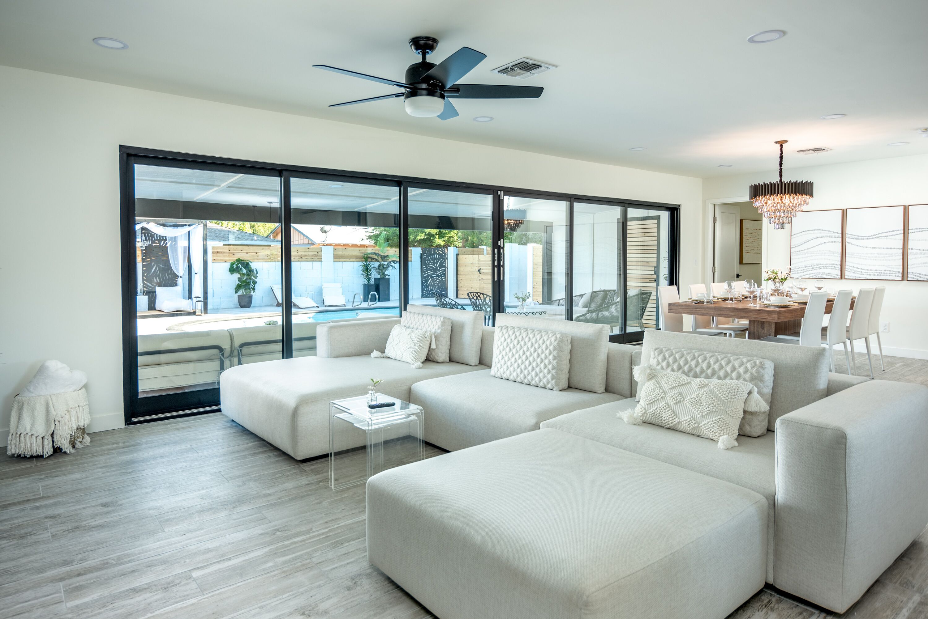 A modern living room with a sectional sofa, a small coffee table, and a dining area with a chandelier.