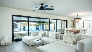 A modern living room with a sectional sofa, a small coffee table, and a dining area with a chandelier. - Scottsdale Luxury Escape (Scottsdale)