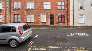 A row of red brick townhouses with white-framed windows and a silver car parked in front.