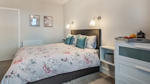 A bedroom with a bed, bedside tables, a dresser, and wall-mounted lamps.
