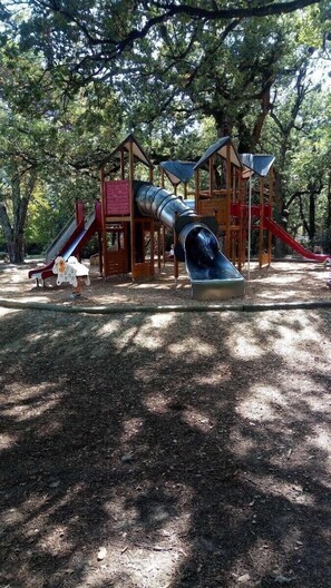 A playground with multiple slides and play structures, surrounded by trees. - Maison Individuelle Dans le Calme et la Verdure (Labarthe-sur-Lèze)