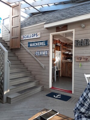 A wooden staircase leading to a bar area with signs for 'SCALLOPS,' 'MACKEREL,' and 'CLAMS.' - Historic Woodbine Cottage  (Tyne Valley)