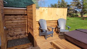 A wooden deck with two Adirondack chairs, a bench, and a small table.