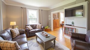 A living room with a sofa, armchairs, a coffee table, and a television.