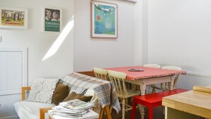 Una habitación acogedora con cama, una mesa y sillas. En la pared, hay cuadros enmarcados.
