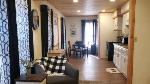 A cozy living room with a sofa, a small side table, and a dining area with a table and chairs. A kitchen is visible in the background. - Park View Place 4 Blocks From the World's Biggest (Casey)
