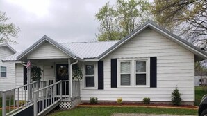 A single-story house with a porch, a front yard with a gravel path, and a small garden area. - Park View Place 4 Blocks From the World's Biggest (Casey)
