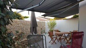 Eine Terrasse mit Tisch, Stühlen, einem Rollstuhl und einem Blumentopf.