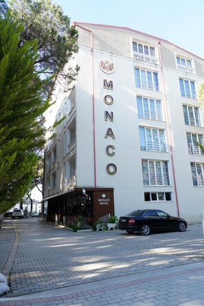 Un edificio con un cartel que dice 'MONACO HOTEL' y un coche estacionado en la calle.