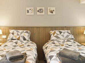 A double room with two beds, each with patterned bedding, wooden headboard, and a small wall art above.