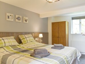 A bedroom with a bed, a wooden wardrobe, and wall art.