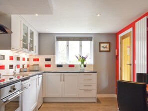 A modern kitchen with white cabinets, a built-in oven, and a window with a view.