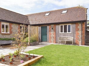 A two-story house with a brick exterior, a green door, and a wooden bench.