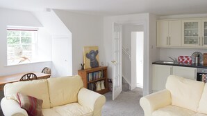 A cozy living room with two cream-colored sofas, a wooden bookshelf, and a dining area with a wooden table and chairs. - 1 bedroom accommodation in Yetholm, near Kelso (Yetholm, near Kelso)