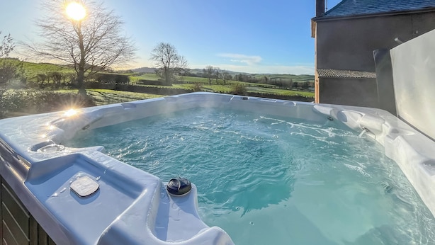 A hot tub with a view of the countryside, a brick wall, and a chimney. - Woodend Farmhouse Halmyre (Haugh of Urr, near Castle Douglas)