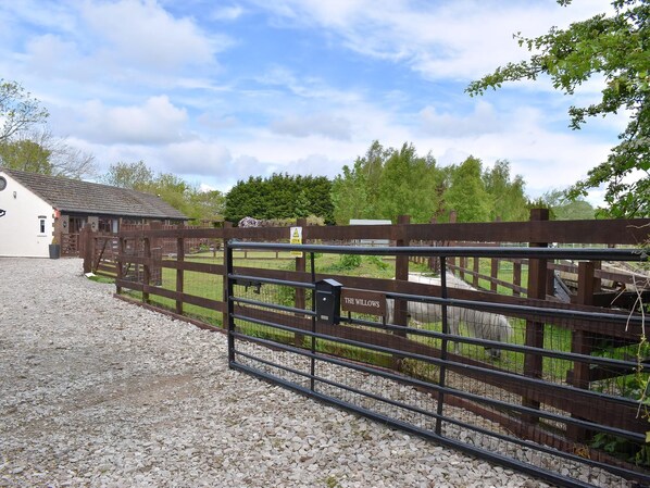 A gravel driveway leading to a wooden gate with a sign reading 'The Willows.' - 1 bedroom accommodation in Out Rawcliffe, near Fleetwood (Out Rawcliffe, near Fleetwood)