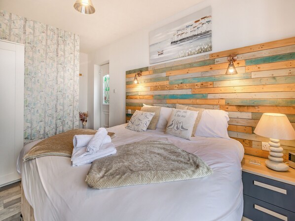 A neatly made bed with pillows, a bedside lamp, and a wall-mounted painting.