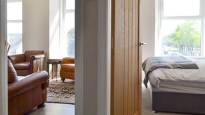 Ein Schlafzimmer mit einem Bett, einer Holztür, einem Fenster und Blick auf die Straße.