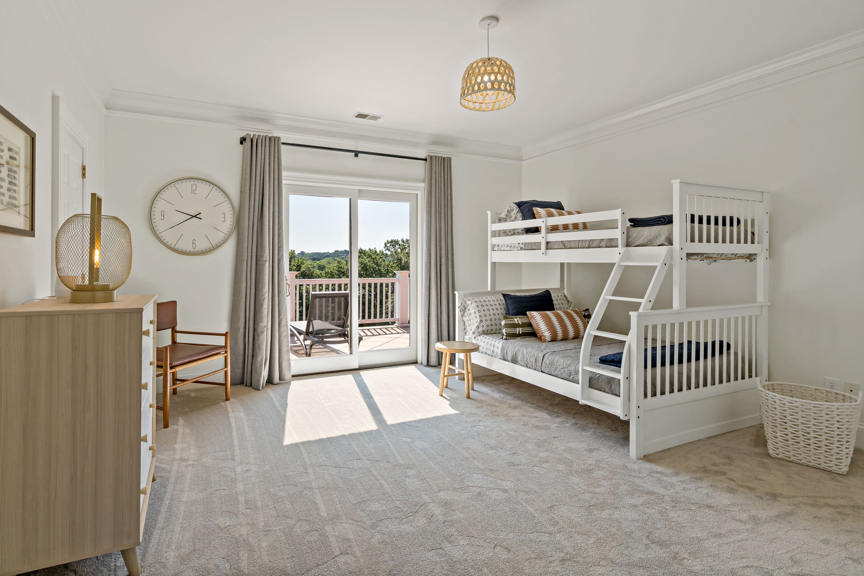 Quarto com cama beliche, escrivaninha, cadeira e vista para o exterior.