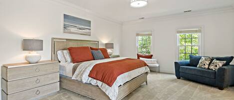 A bedroom with a bed, dresser, nightstands, and a blue sofa.